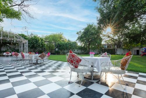 a patio with tables and chairs on a checkered floor at Hotel CASA Aishbagh in Lucknow