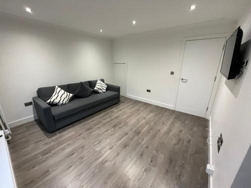 sala de estar con sofá negro y TV en London West Ham Apartments en Londres