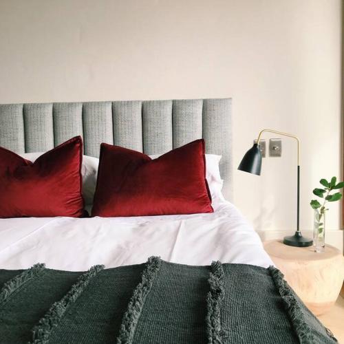 a bed with two red pillows on it with at Cloud 9 Luxury Eco Villa in Sedgefield