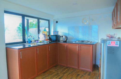 a kitchen with red cabinets and a sink and a refrigerator at Hummingbird St.Clare Villas in Dimbula