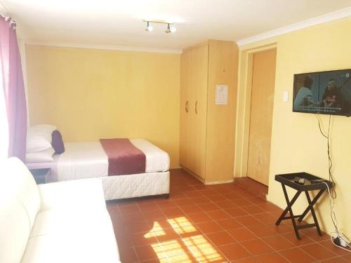 um quarto de hotel com duas camas e uma televisão em Halfway Guests em Polokwane
