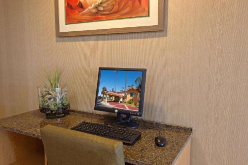 a desk with a computer monitor and a keyboard and mouse at La Quinta Inn by Wyndham Costa Mesa Orange County in Costa Mesa