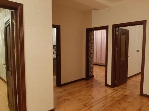 an empty room with three doors and wooden floors at My sweet home in Qara Qarayev in Baku