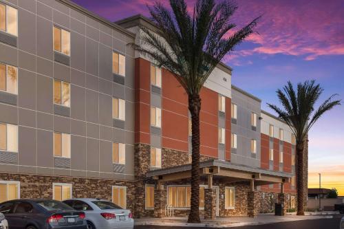 an apartment building with palm trees in front of it at WoodSpring Suites Mesa Chandler in Mesa