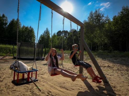 two girls sitting on a swing at a playground at Moje Miejsce Kazimierz in Kazimierz Dolny