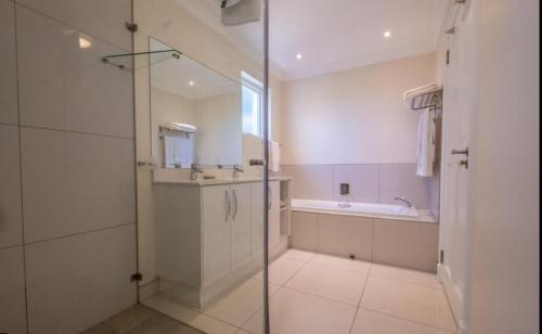 uma casa de banho com um chuveiro, um lavatório e uma banheira em Westhill Luxury Guest House em Knysna