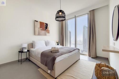 a white bedroom with a bed and a large window at High Floor - Stunning Location - Canal View in Dubai