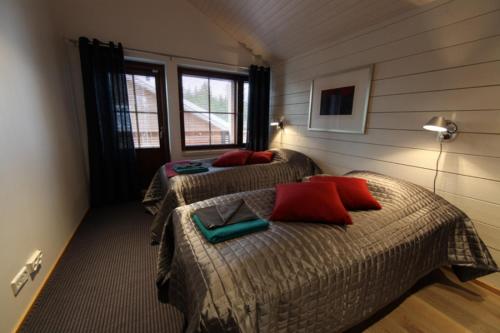 a bedroom with two beds with red pillows at Levi Cirius in Kittilä