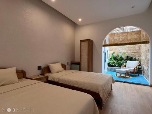 a bedroom with two beds and a window with a chair at MOONLIGHT Homestay & Hotel in Pleiku