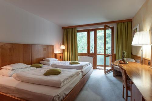 a hotel room with two beds and a desk and window at Hotel Restaurant Südrast Dreiländereck in Arnoldstein