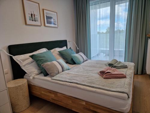 łóżko z poduszkami w pokoju z oknem w obiekcie Apartamenty Rogowo w Rogowie
