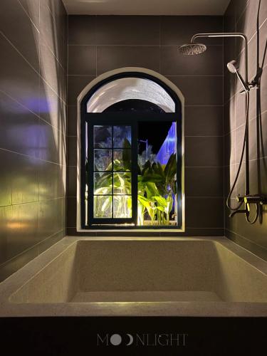 a bath tub with a window in a bathroom at MOONLIGHT Homestay & Hotel in Pleiku