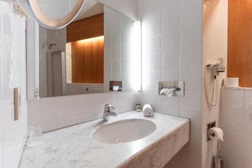 La salle de bains est pourvue d'un lavabo et d'un miroir. dans l'établissement Hotel Restaurant Südrast Dreiländereck, à Arnoldstein
