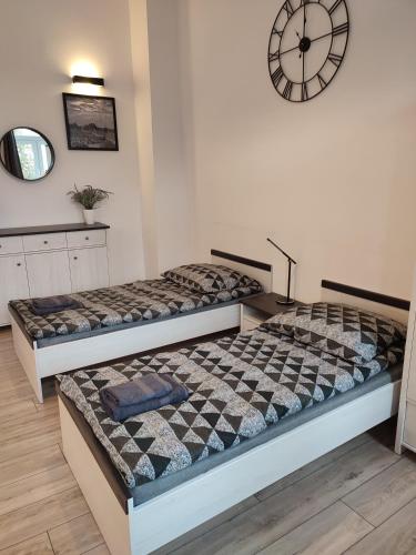two beds in a room with a clock on the wall at Suwałki Centrum Apartments 1 & 2 in Suwałki