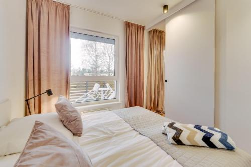 een slaapkamer met een bed voor een raam bij Apartament SAND SurfingBird Dźwirzyno in Dźwirzyno