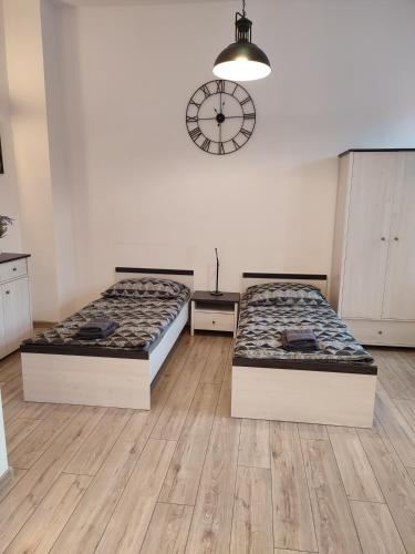 two beds in a room with a clock on the wall at Suwałki Centrum Apartments 1 & 2 in Suwałki