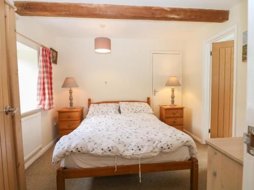 a bedroom with a bed and two dressers and a window at Byre Cottage 1 in Pulborough