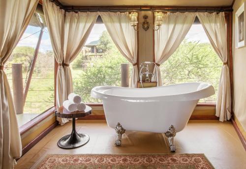 een badkamer met een bad voor een raam bij TARANGIRE KURO TREETOP LODGE in Manyara