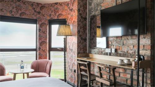 Avoca Hotel في نيوكاسل: غرفة نوم بحائط من الطوب وطاولة وكراسي