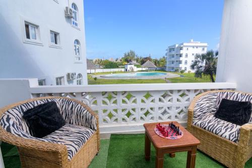 two chairs and a coffee table on a balcony at Cozy Crib in Malindi