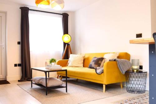 a yellow couch in a living room with a table at Lovely 1 BR Headington apartment with FREE parking in Oxford