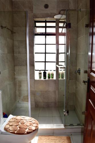 a bathroom with a shower with a toilet and a window at Cheerful 4-bedroom with pool in Athi River
