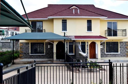 a house with a black fence in front of it at Cheerful 4-bedroom with pool in Athi River