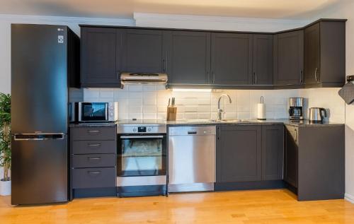 una cocina con electrodomésticos de acero inoxidable y armarios negros en City Square en Tromsø