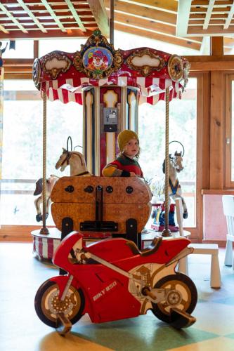 a child riding a merry go round on a carousel at Hotel Restaurant Südrast Dreiländereck in Arnoldstein