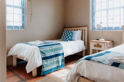 a bedroom with two beds and two windows at Duifie in Paternoster