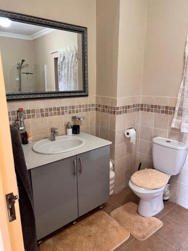 a bathroom with a sink and a toilet and a mirror at Ocean View Villas: Port Edward Unit H09 in Port Edward
