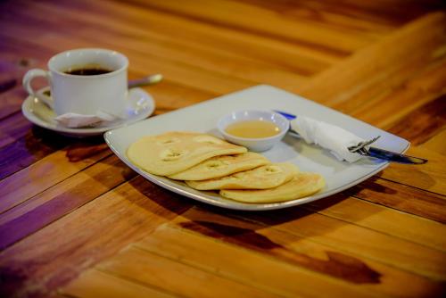 a plate of pancakes and a cup of coffee on a table at The Granyam Garden Cottage in Nusa Penida