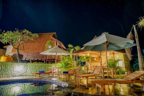 a patio with chairs and umbrellas and a pool at The Granyam Garden Cottage in Nusa Penida