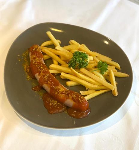 a plate of food with a hot dog and french fries at Hotel Restaurant Südrast Dreiländereck in Arnoldstein