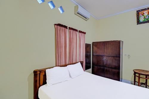 ein Schlafzimmer mit einem Bett, einem Stuhl und einem Tisch in der Unterkunft OYO 91738 Ciung Wanara Guest House in Denpasar