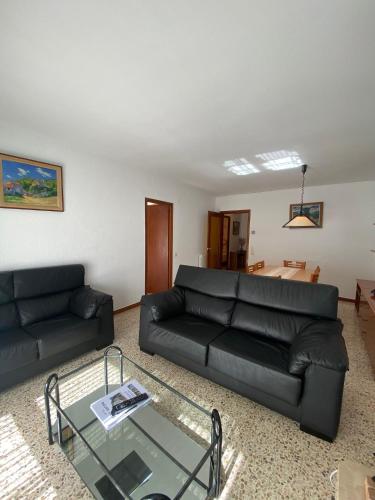 a living room with a black couch and a glass table at Apartaments Sant Antoni in Ribes de Freser