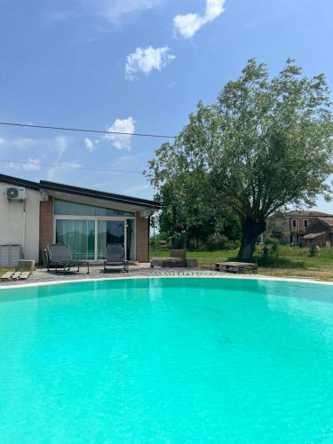une grande piscine bleue en face d'une maison dans l'établissement Cottage indipendente con piscina privata, à Masi San Giacomo