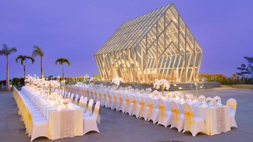 a row of tables with white chairs and a glass building at InterContinental Bandung Dago Pakar by IHG in Bandung