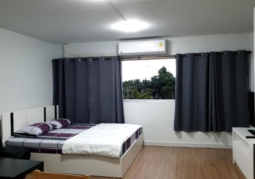a bedroom with a bed with black curtains and a window at ห้องพักรายวัน เมืองทองธานี เรือนศรีตรัง in Ban Bang Phang