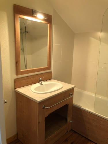 y baño con lavabo, espejo y bañera. en Chalet cosy Duplex 6 personnes, en Saint-Sorlin-dʼArves