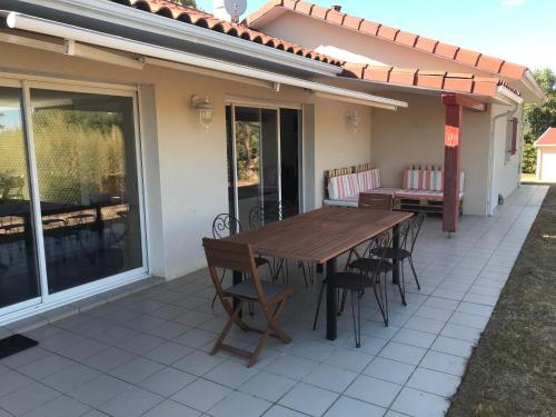 une table et des chaises en bois sur une terrasse dans l'établissement Villa avec son spa privatif proche de Rocamadour, à Gramat