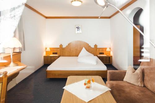 ein Hotelzimmer mit einem Bett und einem Sofa in der Unterkunft Hotel Klausnerhof in Tux