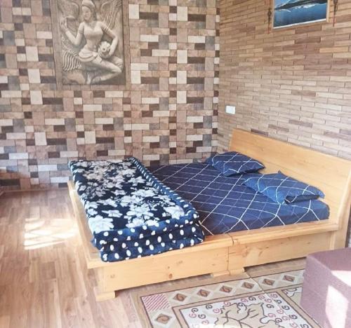 a wooden bed in a room with a wall at Anuppam Home Stay in Kulu