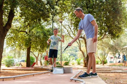 a man and a child playing in a park at MASLINICA Hedera Hotel in Rabac