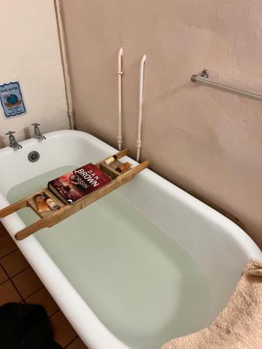 a bath tub with a book on top of it at Back o' the Moon Holiday cottage in Hogsback