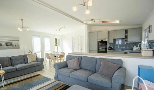 a living room with two couches and a kitchen at The Warren Holiday Park - Family Chalet in Abersoch