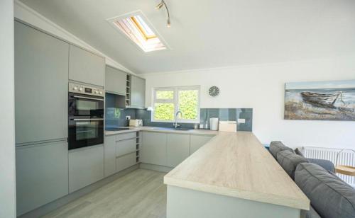 a kitchen with white cabinets and a wooden counter top at The Warren Holiday Park - Family Chalet in Abersoch