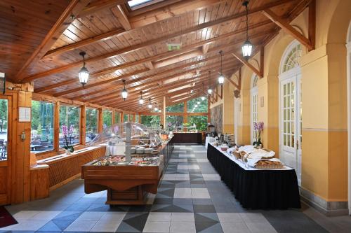 a large room with tables in a building with windows at Hotel Eger & Park in Eger