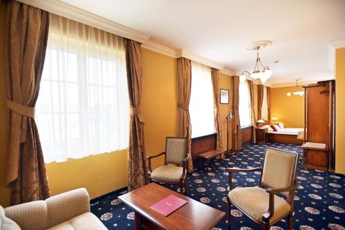 a hotel room with a table and chairs and a bed at Hotel Eger & Park in Eger