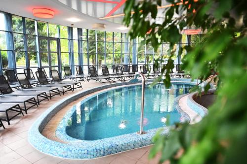a large swimming pool in a building with chairs at Hotel Eger & Park in Eger